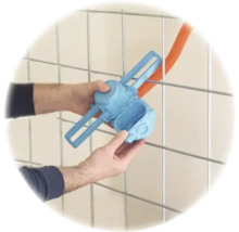 Hände montieren eine blaue Elektro-Installationsdose an ein Metallgitter mit einem orangefarbenen Leerrohr.