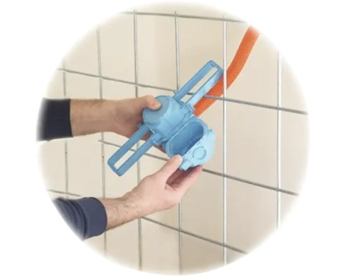 Hände montieren eine blaue Elektro-Installationsdose an ein Metallgitter mit einem orangefarbenen Leerrohr.