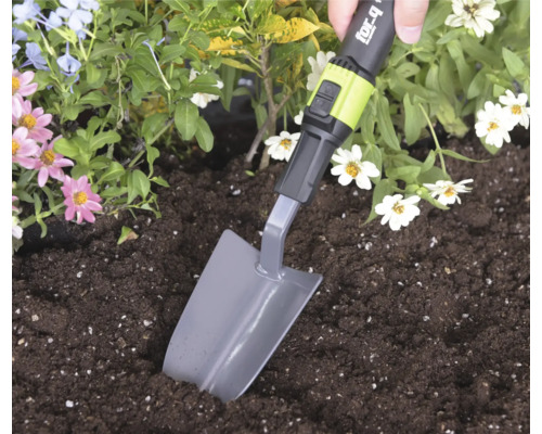 Eine Hand nutzt eine for_q Pflanzkelle zum Graben in Erde in einem Blumenbeet.