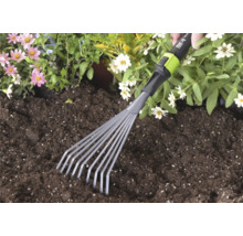 Handgeführter kleiner Fächerbesen von for_q wird in dunkler Blumenerde neben rosa und weißen Blumen verwendet.