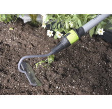 Gartenhacke aus Metall bei der Gartenarbeit in Erde neben einer Pflanze.