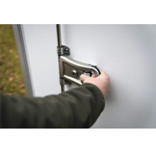 Hand bedient einen Metall-Hebelverschluss mit Schließzylinder an einer weißen Tür.