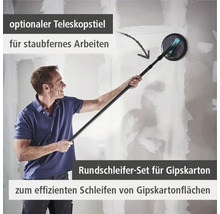 Ein Mann schleift eine Gipskartonwand mit einem Rundschleifer und einem optionalen Teleskopstiel für staubfernes Arbeiten.