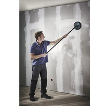 Ein Mann schleift eine Trockenbauwand mit einem Langhalsschleifer mit Teleskopstange.