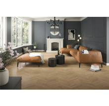 Großzügiges modernes Wohnzimmer mit Bodenbelag in Holzoptik im Fischgrätmuster, Wänden mit Zierleisten, einem großen Ledersofa und einem Kamin.