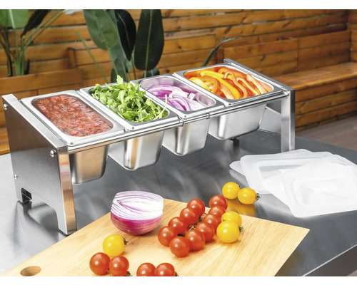 Edelstahl-Beilagenbehälter mit vier Fächern, gefüllt mit frischem Gemüse und Sauce auf einem Arbeitstisch.