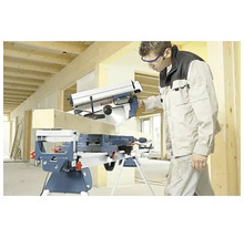 Handwerker schneidet Holzbalken mit einer Bosch Kapp- und Gehrungssäge auf einem Arbeitstisch in einem hellen Rohbau.