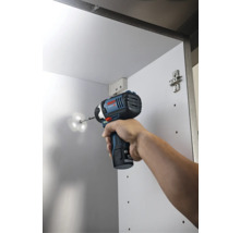 Bosch Akku-Drehschlagschrauber beim Einschrauben einer Schraube in einen weißen Schrank.