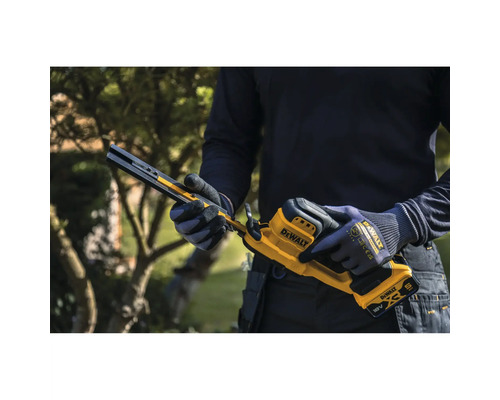 Person hält eine DeWalt 18 Volt Akku-Bandsäge mit Arbeitshandschuhen in einem Garten.