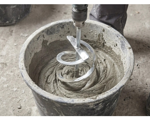 Ein Wendelrührer rührt grauen Mörtel in einem schwarzen Mörtelkübel an.