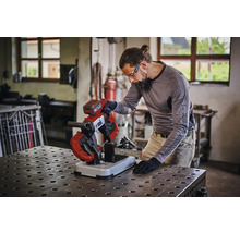 Eine Person benutzt eine Akku Metallbandsäge zum Schneiden eines Metallprofils auf einer Werkbank in einer Werkstatt.