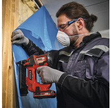 Handwerker mit Schutzausrüstung befestigt eine Dampfsperrfolie an einem Holzständer mit einem Einhell Akku-Nagler.