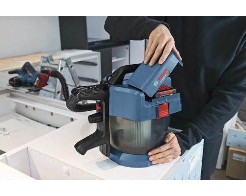 Eine Person setzt einen 18 Volt Akku in einen Bosch Professional Akku-Staubsauger GAS 18 Volt-1 in einer Werkstatt ein.