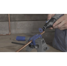 Mit einem Dremel Multifunktionswerkzeug und einer Trennscheibe wird ein Kupferrohr geschnitten, das in einem Schraubstock eingespannt ist.