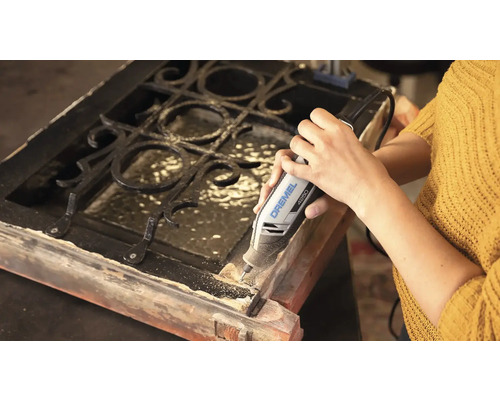 Person nutzt ein Dremel 4250 Multifunktionswerkzeug zum Bearbeiten eines Holzrahmens mit Metallgitter.