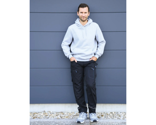 Mann in Arbeitskleidung bestehend aus einem grauen Kapuzenpullover und einer schwarzen Arbeitshose.