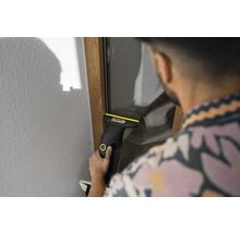 Person reinigt eine Fensterscheibe mit einem Kärcher Akku-Fenstersauger.