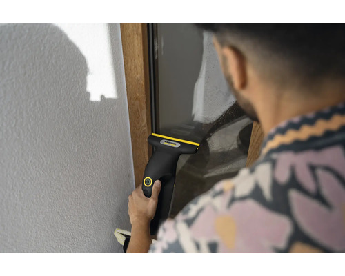 Person reinigt eine Fensterscheibe mit einem Kärcher Akku-Fenstersauger.