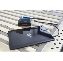 Bosch Professional USB Akku Adapter GAA 18 Volt 24 lädt ein Tablet mit einem ProCORE 18 Volt Akku auf einer Werkbank.