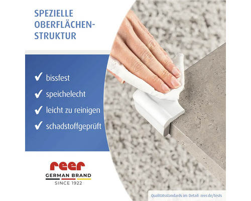 Hand reinigt einen weißen, bissfesten und speichelechten Eckenschutz an einer Tischkante. Leicht zu reinigen und schadstoffgeprüft. reer Logo.