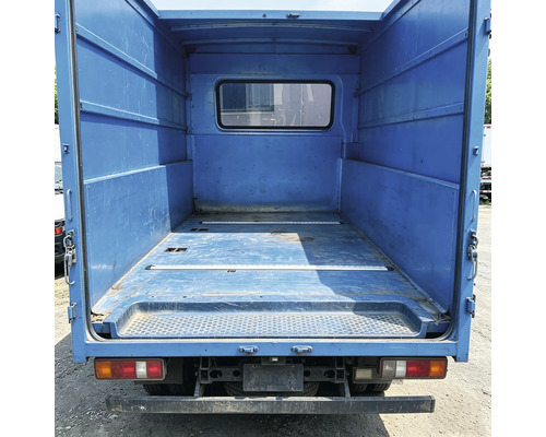 Leere Ladefläche eines Transporters mit Metallwänden und einem Fenster in der Trennwand.