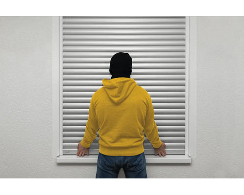 Einbruchschutz am Fenster durch einen geschlossenen Rollladen mit einer Person davor.