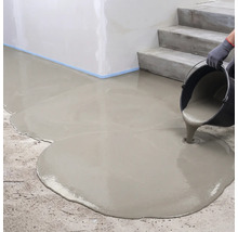 Ausgießen von flüssiger Bodenausgleichsmasse aus einem Eimer auf einen Betonboden neben einer Treppe.