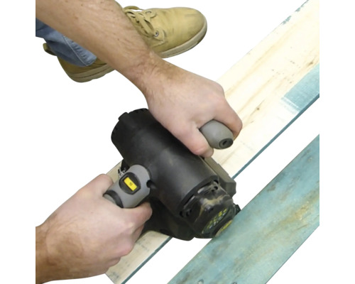 Eine Person verwendet einen elektrischen Handhobel zur Bearbeitung von Holzbrettern.