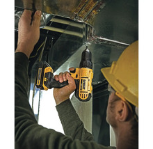 Handwerker mit gelbem Schutzhelm nutzt einen DeWalt Akku-Bohrschrauber zur Montage an einem Lüftungskanal aus Metall.