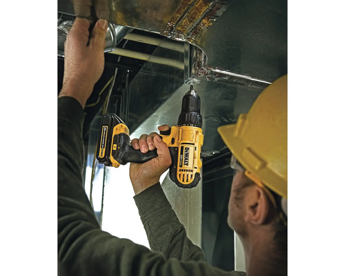 Handwerker mit gelbem Schutzhelm nutzt einen DeWalt Akku-Bohrschrauber zur Montage an einem Lüftungskanal aus Metall.
