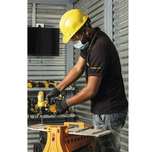 Handwerker mit Schutzhelm nutzt DeWALT Akku-Bohrschrauber an einem Sägebock in einer hellen Werkstatt mit Metallwänden.