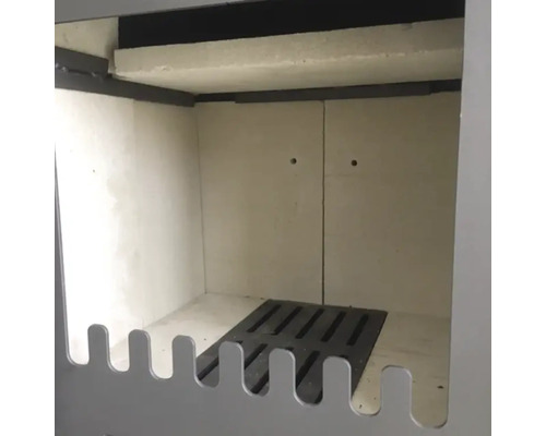 Innenraum eines Kaminofens mit Schamottsteinauskleidung und Ascherost aus Gusseisen.