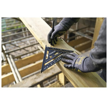 Eine Person mit Arbeitshandschuhen markiert einen Holzbalken mit einem Stanley Sparrenwinkel und einem Bleistift in einer hellen Baustellumgebung.