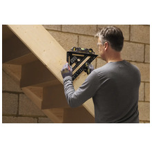 Ein Handwerker markiert eine Holztreppe mit einem schwarzen Zimmermannswinkel inklusive integrierter Wasserwaage.