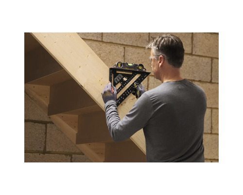 Ein Handwerker markiert eine Holztreppe mit einem schwarzen Zimmermannswinkel inklusive integrierter Wasserwaage.