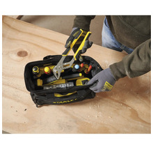 Person entnimmt eine Wasserpumpenzange aus einer Stanley Werkzeugtasche auf einer Werkbank aus Holz.