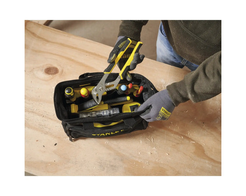 Person entnimmt eine Wasserpumpenzange aus einer Stanley Werkzeugtasche auf einer Werkbank aus Holz.