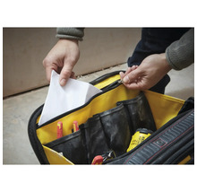 Geöffnete Werkzeugtasche mit mehreren Innenfächern, Schraubendrehern, Bohrer und einem Dokument.