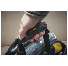 Hand am gepolsterten Tragegriff einer Stanley Werkzeugtasche mit roten Ziernähten.
