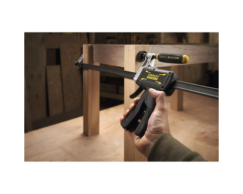 Stanley FatMax Einhandzwinge fixiert Holzbauteile an einem Möbelstück in einer Werkstatt.
