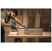 Ein Handwerker nutzt eine Stanley Fatmax Einhandzwinge, um zwei Holzbalken auf einer Werkbank in einer hellen Werkstatt zu fixieren.