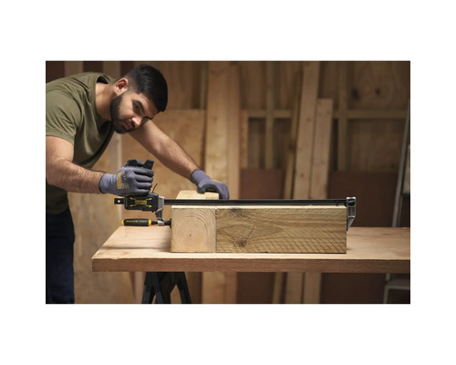 Ein Handwerker nutzt eine Stanley Fatmax Einhandzwinge, um zwei Holzbalken auf einer Werkbank in einer hellen Werkstatt zu fixieren.