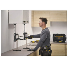 Ein Handwerker nutzt zwei Stanley FatMax TradeLift Hebewerkzeuge, um einen Küchenschrank präzise an der Wand zu positionieren und zu montieren.