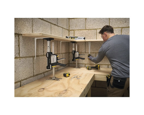 Ein Mann montiert Holzregale in einer Werkstatt mit Stanley Trade Lifts zur Unterstützung, einer Wasserwaage und einem Maßband.