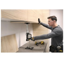 Ein Handwerker nutzt den Stanley TradeLift zur präzisen Montage eines Küchenoberschranks aus hellem Holz über einer grauen Arbeitsplatte.