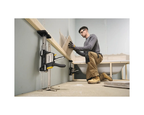 Ein Handwerker nutzt einen Stanley Trade Lift zur Abstützung eines Holzbalkens bei der Fliesenverlegung im Badezimmer während der Renovierung.