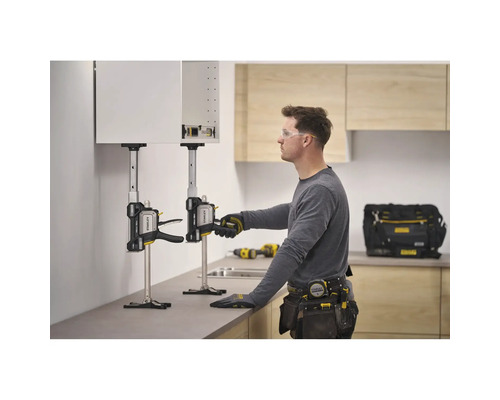 Ein Handwerker nutzt zwei Stanley FatMax TradeLift Hebewerkzeuge, um einen Küchenschrank präzise an der Wand zu positionieren und zu montieren.