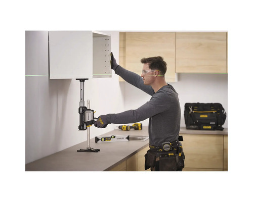 Ein Handwerker nutzt einen Stanley TradeLift zum präzisen Anheben eines Küchenschranks in einer hellen Küche mit Holzelementen.