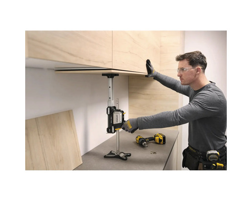 Ein Handwerker nutzt den Stanley TradeLift zur präzisen Montage eines Küchenoberschranks aus hellem Holz über einer grauen Arbeitsplatte.