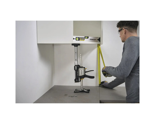 Montage eines Wandschranks mit dem Stanley FatMax Trade Lift zur Abstützung, einer Wasserwaage und einem Maßband in einer hellen Küche.